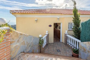 A house with a tiled roof, a stone staircase, and a small garden area. - Villa Olympo by Solset (Torrox)