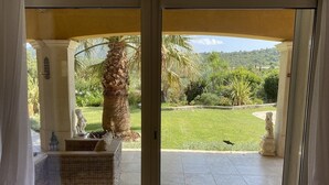 Un porxo cobert amb mobles de vimetla, una palmera i estàtues.