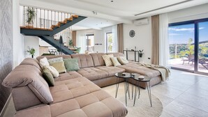 A spacious living area with a large sectional sofa, a staircase, and a view of the outdoors. - Villa Top Hill,heated pool,Jacuzzi,Sauna,5 en-suite bedrooms,Media room (Tugare)