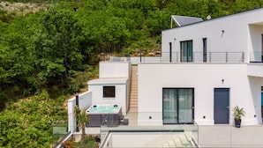 A modern two-story building with a rooftop jacuzzi, large windows, and a balcony overlooking a lush green landscape. - Villa Top Hill,heated pool,Jacuzzi,Sauna,5 en-suite bedrooms,Media room (Tugare)