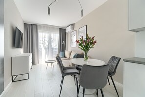 Un salon moderne comprenant un canapé, une table à manger, des chaises et un téléviseur fixé au mur.