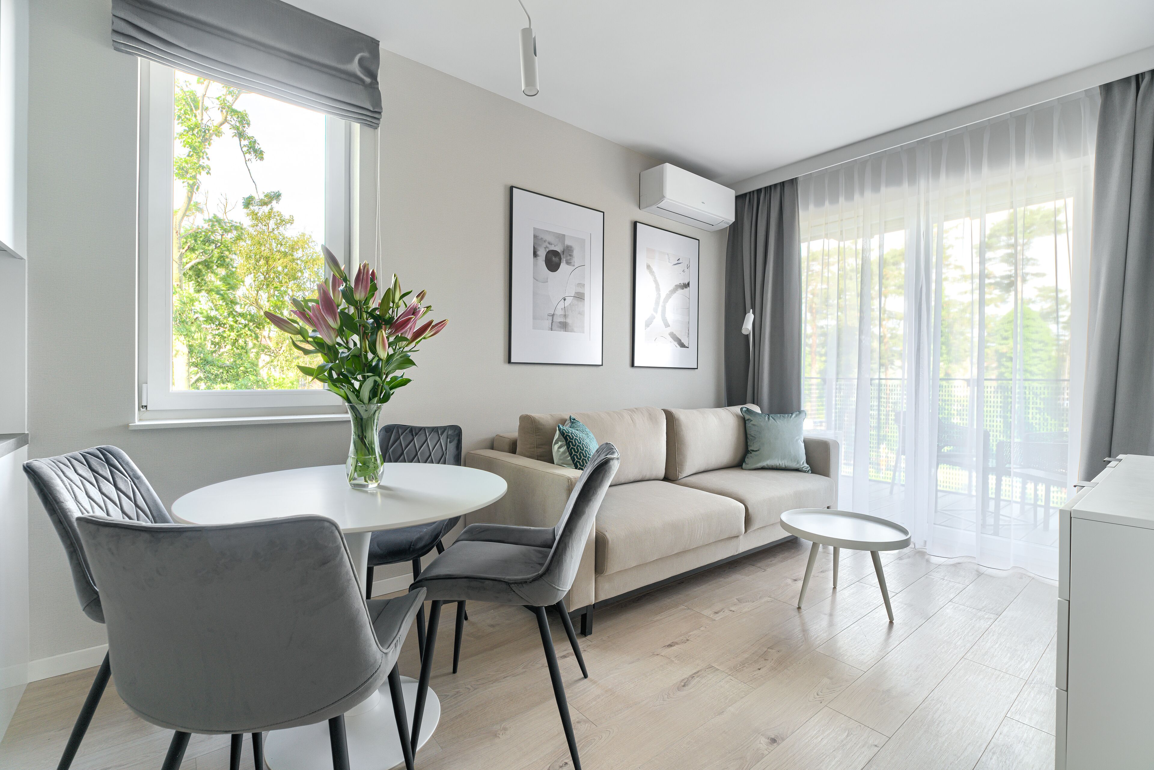 A modern living room with a sofa, two chairs, a small table, and a vase of flowers.