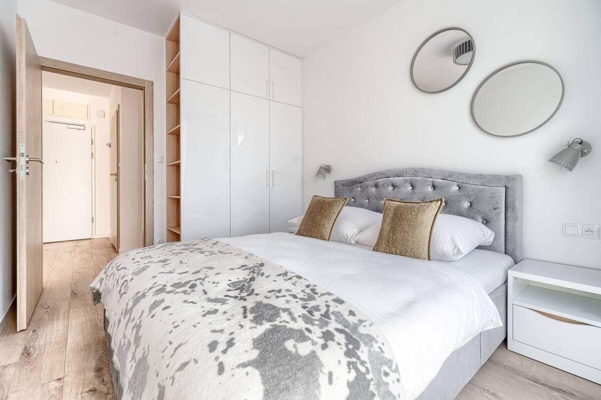 A bedroom with a bed, bedside tables, a wardrobe, and a mirror on the wall.