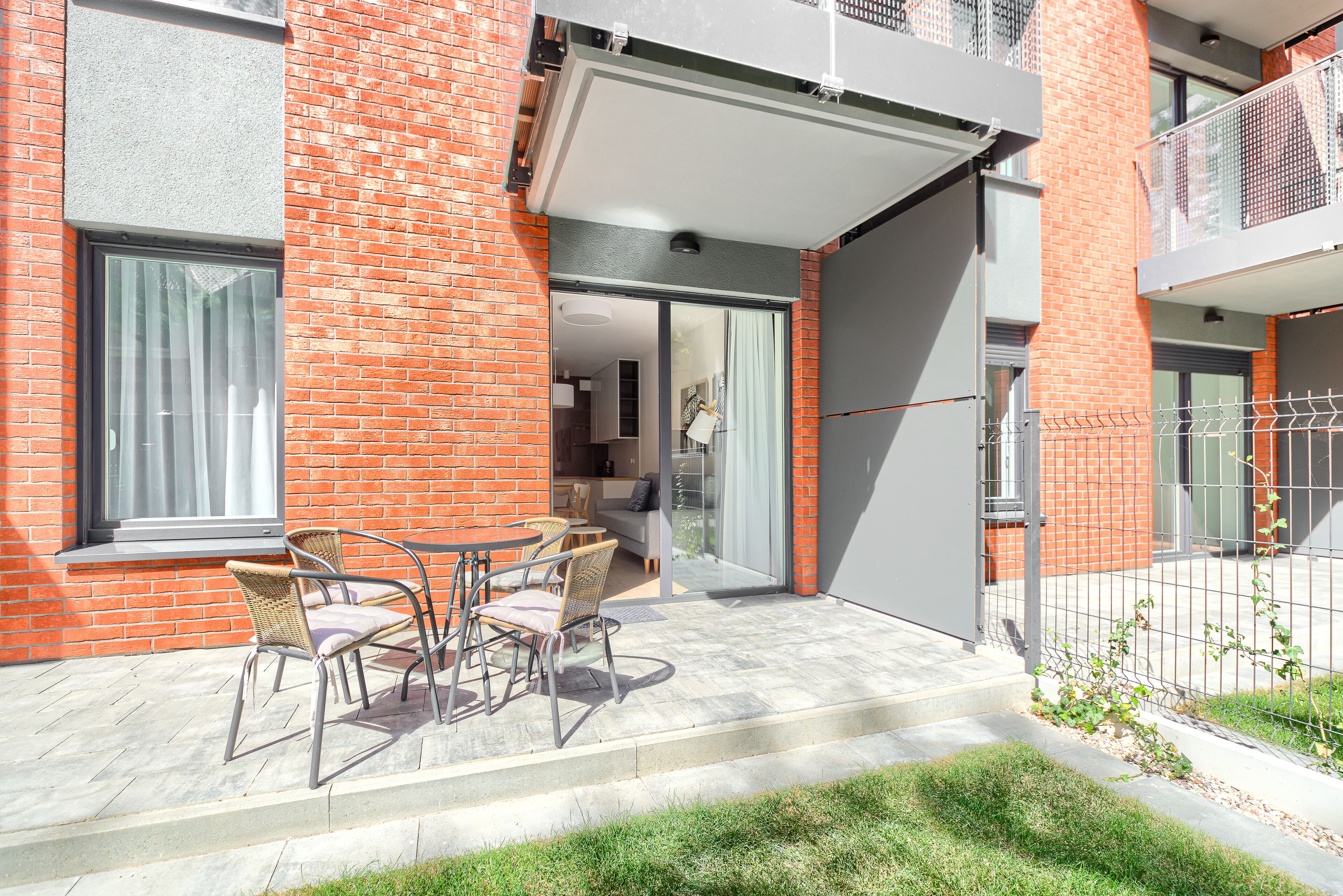 Une terrasse avec des meubles d’extérieur et une porte-fenêtre coulissante donnant sur un espace intérieur.
