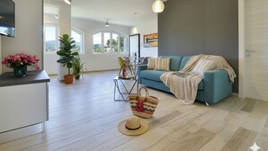 Un salón amplio con sofá, televisor, mesa de comedor y plantas en macetas.