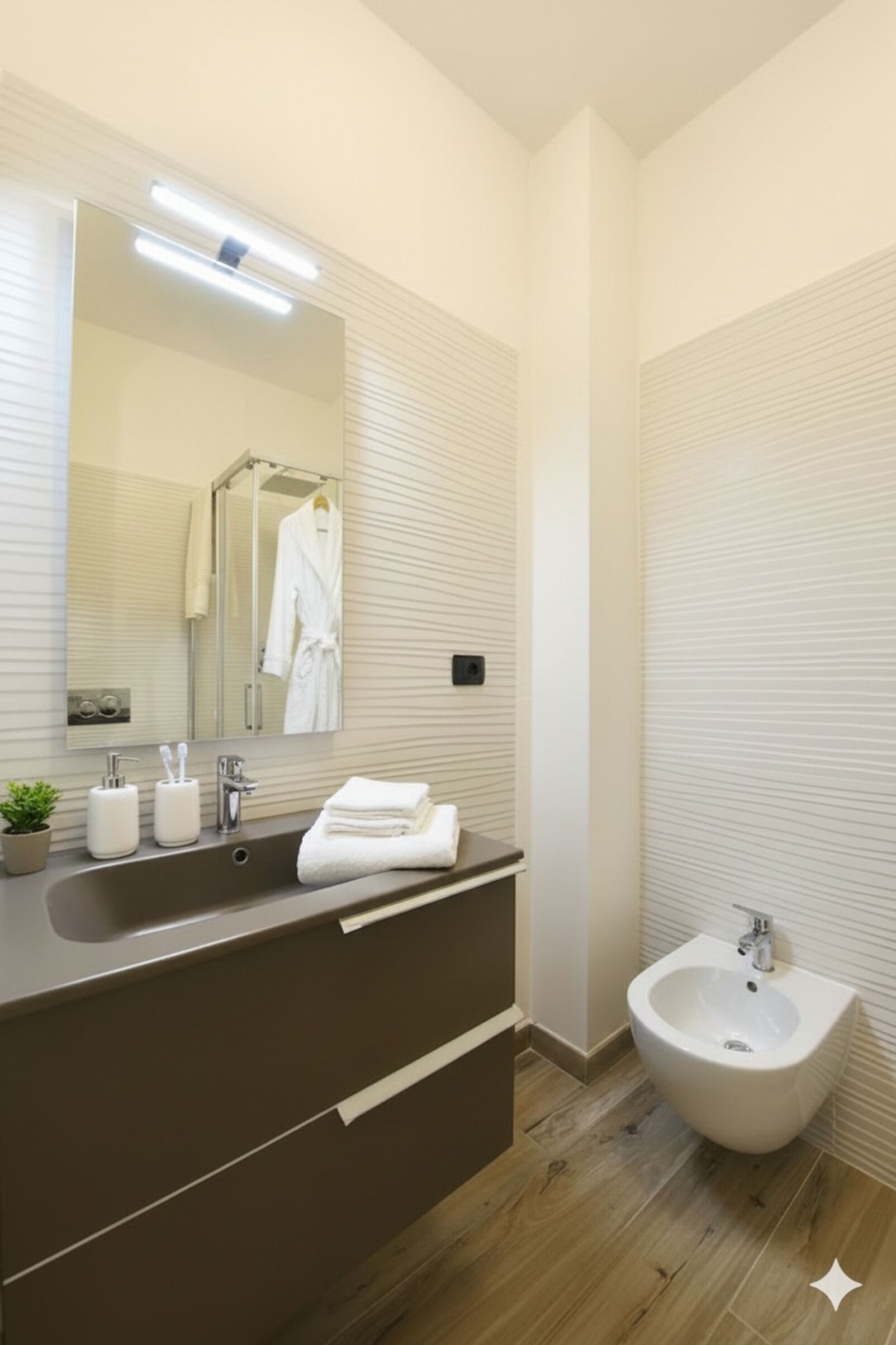 A modern bathroom with a large mirror, a sink, a bidet, and a towel rack.
