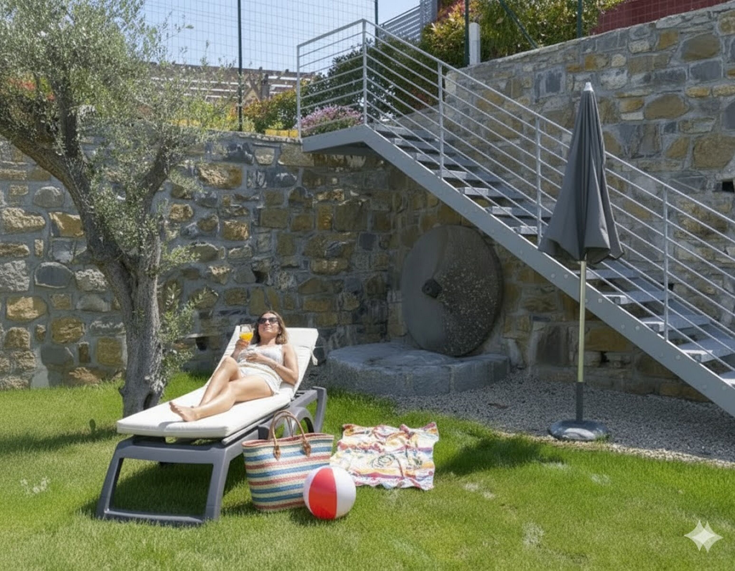 Una persona relaxant-se en una cadira de sol en un jardí amb una paret de pedra i una escala.