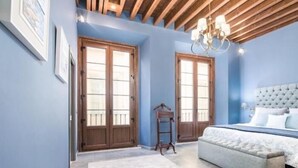 A bedroom with a large bed, wooden ceiling beams, and a chandelier. - iloftmalaga Luciano Martínez (Málaga)