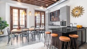 A modern kitchen with a central island, bar stools, and pendant lighting. - iloftmalaga Luciano Martínez (Málaga)