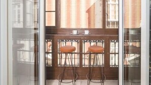 A room with a large window, two stools, and a small table with cups. - iloftmalaga Luciano Martínez (Málaga)