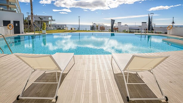 A swimming pool with two lounge chairs and a tiled deck. - iloftmalaga Panoramica II - El Higueron (Fuengirola)