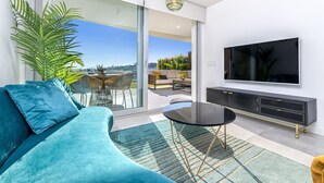 A modern living room with a sofa, a TV, and a dining area with a table and chairs. - iloftmalaga Panoramica II - El Higueron (Fuengirola)