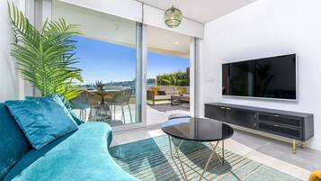 Ein modernes Wohnzimmer mit einer Couch, einem Fernseher und einem Essbereich mit Tisch und Stühlen.