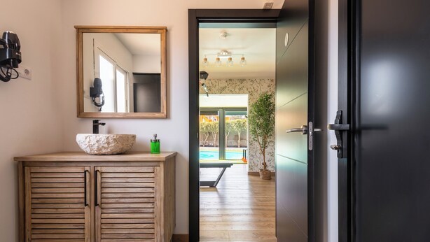 Un baño con tocador de madera, un espejo grande y vistas a una piscina al aire libre.