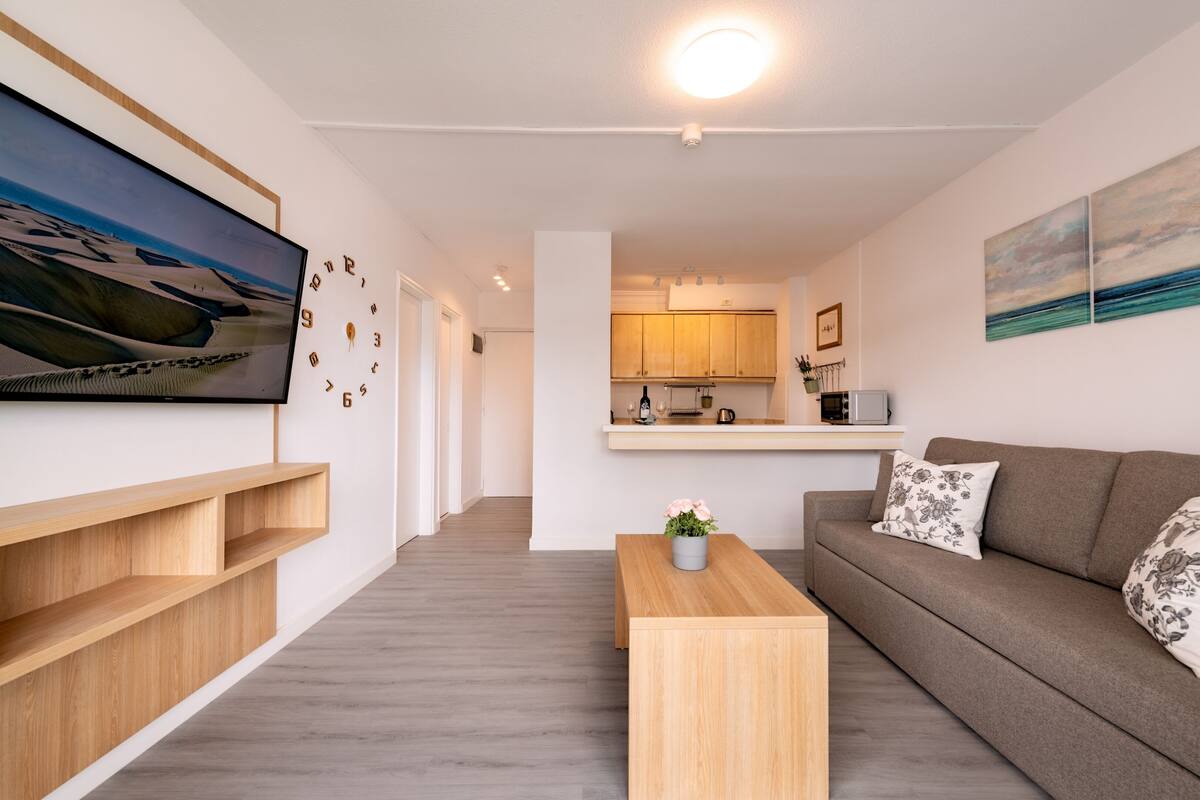 Un salon moderne avec un canapé, une table basse et un téléviseur fixé au mur.
