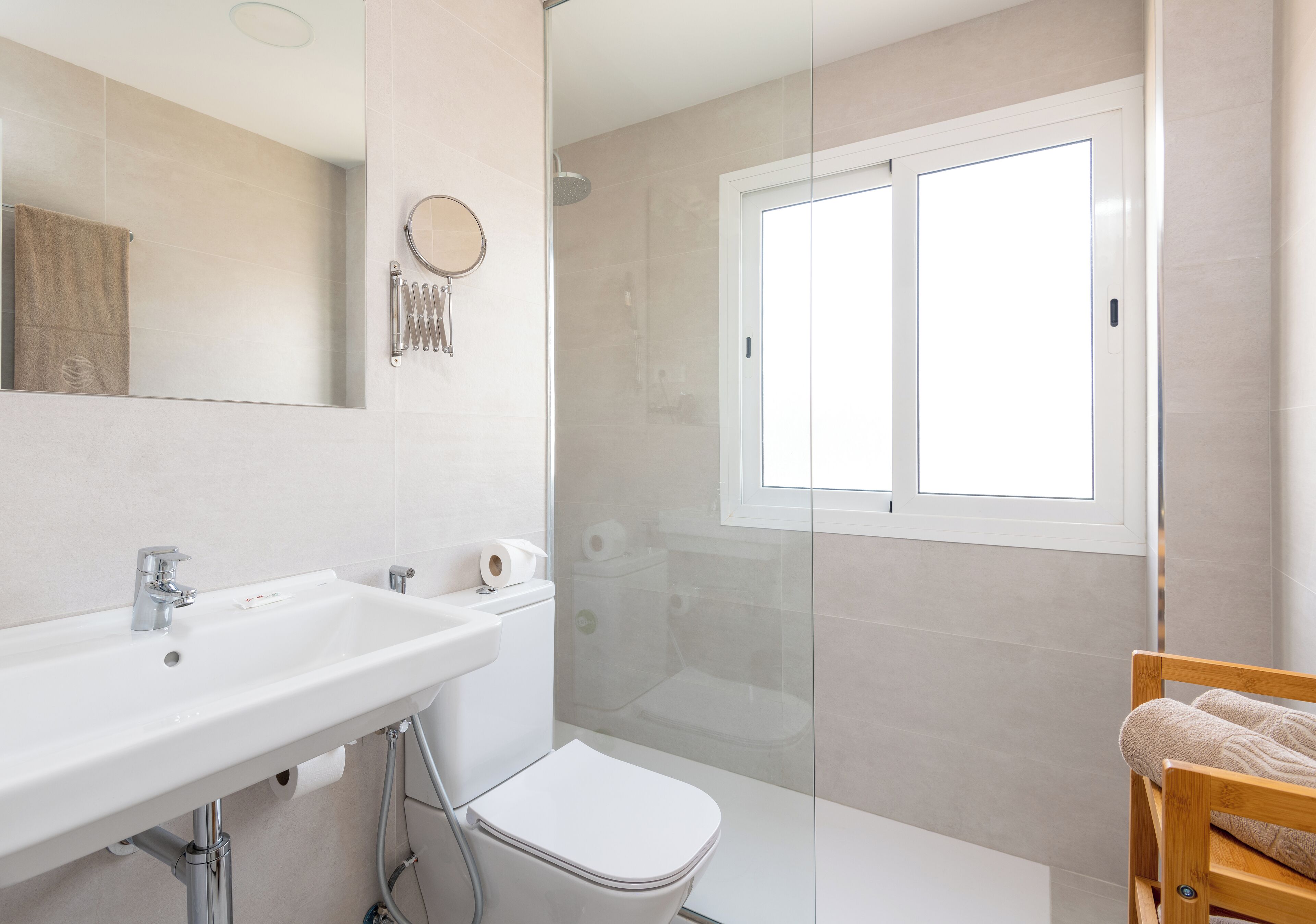 Une salle de bain moderne avec un lavabo blanc, des toilettes et une douche à parois de verre.
