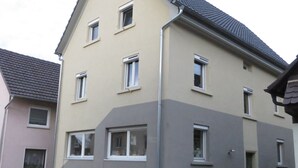 A multi-story residential building with a flat roof and multiple windows.