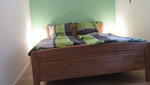 A single bed with a wooden frame and a green and gray striped bedspread.