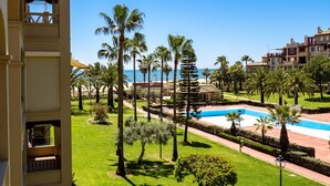 A resort with a pool, palm trees, and a view of the sea. - Alcaudon - Isla Canela Beach IAHL59P273 (Isla Canela)