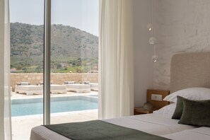 Una camera da letto con un letto, un comodino e vista su una piscina e delle montagne.