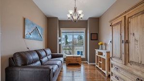 A living room with a leather sofa, wooden cabinet, and a chandelier.