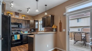 A kitchen with dark wood cabinets, a central island, and a sliding glass door leading to an outdoor patio.