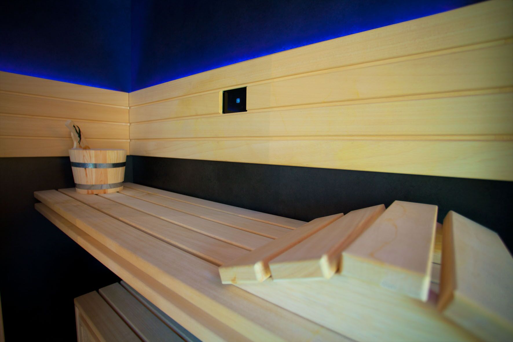 A wooden massage table with a headrest and a small bucket with a towel.