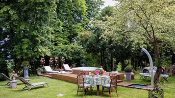 Un jardin avec un jacuzzi, des chaises longues, une table à manger et une terrasse.