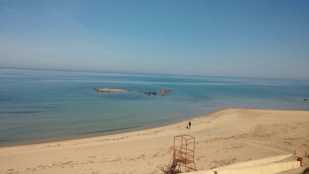 Een strand met helderblauw water, een wachthuis en een zandstrand.