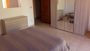 Een slaapkamer met een bed, een kledingkast en een spiegel aan de muur.