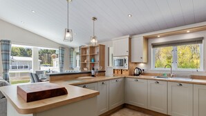 A modern kitchen with a central island, wooden countertops, and built-in appliances. - St Mary's View - Luxury Lodge, Close to Beach (Tenby)