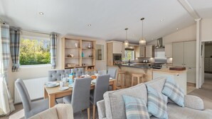 A modern kitchen with a central island, wooden cabinets, and a built-in oven. - St Mary's View - Luxury Lodge, Close to Beach (Tenby)