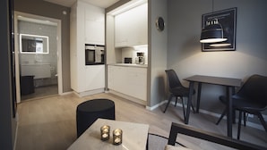 A modern kitchen with white cabinets, a dining area with a table and chairs, and a pendant light above the table. - Sky Hotel Apartments Hospitalstorget (Linkoping)