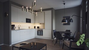 A modern kitchen with white cabinets, a dining area with a table and chairs, and a pendant light fixture. - Sky Hotel Apartments Hospitalstorget (Linkoping)