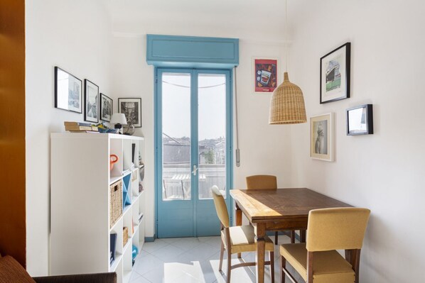 A dining area with a wooden table and chairs, a white bookshelf, and a blue-framed door. - The blue nest with a view - Palestrina (Milano)