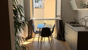 Cozinha compacta com área de refeições, vista para edifícios e uma planta em vaso.