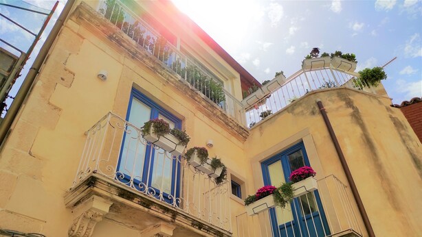 A building with two balconies, each with blue-framed windows and white railings. - Suite Bagnara (Syracuse)