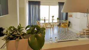 A dining area with a glass table, yellow chairs, and blue curtains. - Suite Bagnara (Syracuse)