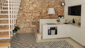 A modern kitchen with white cabinets, a stone wall, a built-in oven, and a patterned floor. - Suite Bagnara (Syracuse)