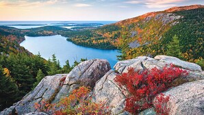 A mountainous landscape with a lake surrounded by autumn foliage.