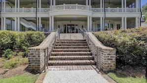 A large, two-story building with a central entrance, a covered porch with columns, and a staircase leading to the entrance.
