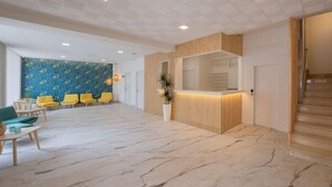 En hotelllobby med en receptionsdisk, en sittgrupp och en trappa.