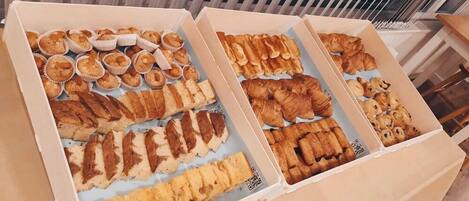 Two open boxes of assorted pastries on a wooden floor.