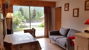 Ein gemütliches Zimmer mit einem Holztisch, einem grauen Sofa und einer roten Lampe.