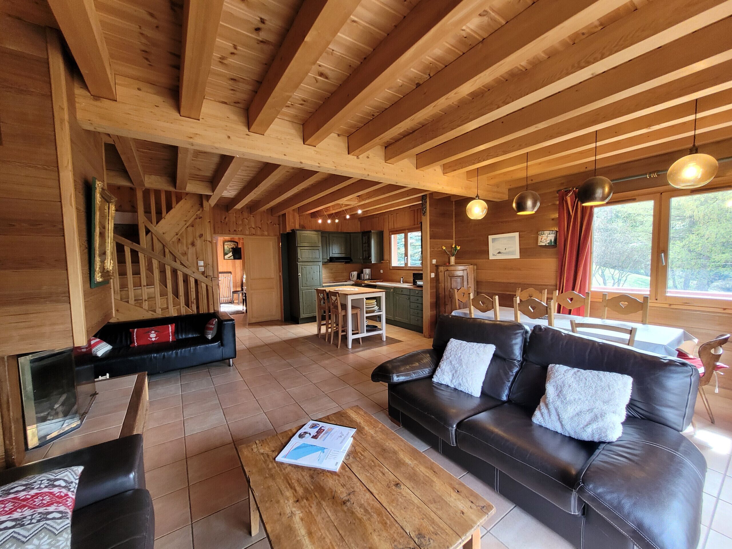 L’intérieur d’une cabane en bois comprend un espace de vie, une table à manger, une cuisine et un escalier.
