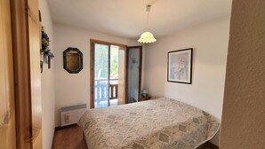 A bedroom with a bed, a door, a window, and a ceiling light. - AT THE FEET OF THE SKI SLOPES- FLAT  4 PEOPLE (Chantemerle)