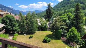 A residential area with a well-maintained lawn, a wooden deck, and a view of a mountain range. - AT THE FEET OF THE SKI SLOPES- FLAT  4 PEOPLE (Chantemerle)