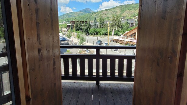 A wooden balcony with a view of a town, mountains, and a clear sky. - AT THE FEET OF THE SKI SLOPES- FLAT  4 PEOPLE (Chantemerle)