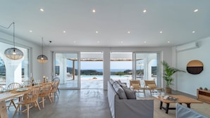 A spacious living area with a pool view, a dining area with wooden furniture, and a modern design. - Nora Villa in Afandou (Rhodes)