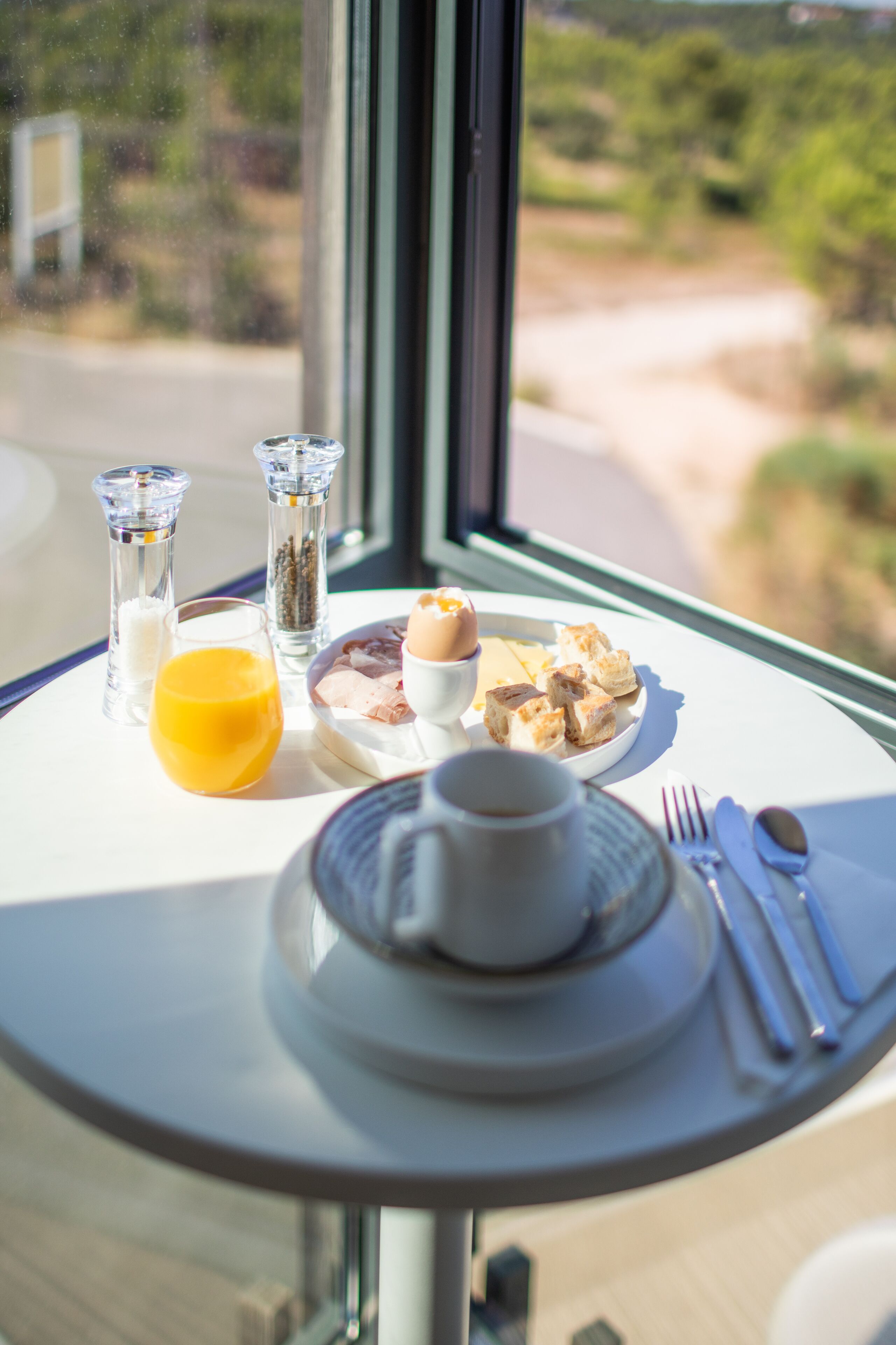 A dining table with a meal, salt and pepper shakers, a glass of orange juice, and a cup of coffee.